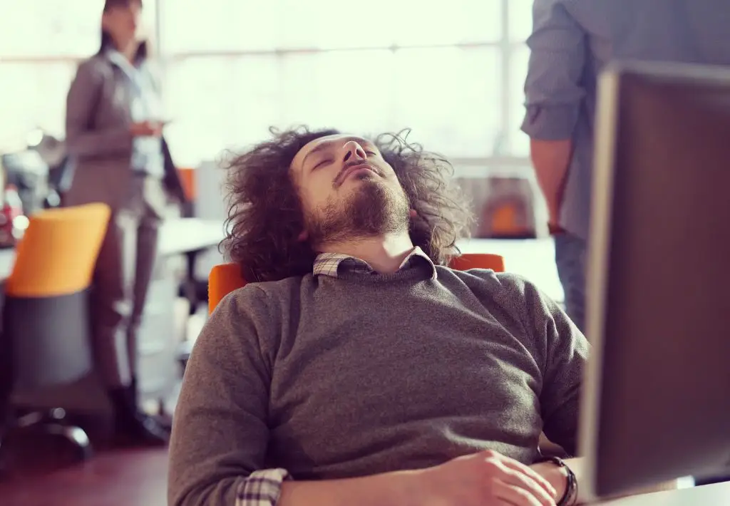 a young man is passed out at his computer because he is experiencing low testosterone - one of the core areas of focus for protocols that assist with anti aging for men.
