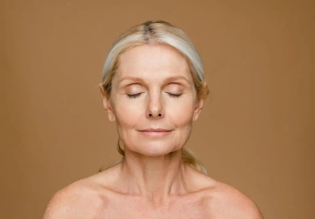 a calm expression is on the face of an older woman. Her eyes are closed and she is relaxed because she knows that anit aging for women can unleash inner beauty.