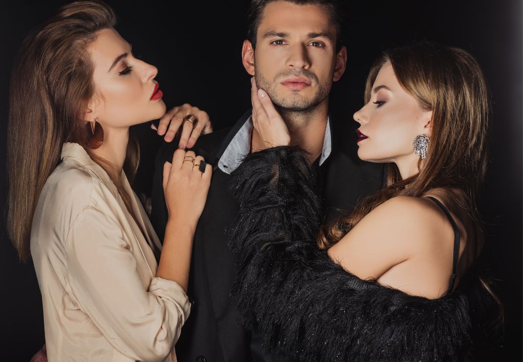 an unshaved young man in business casual clothing is surrounded by two very attractive and lustful model types. This suggests that anti aging for men drives gains in sexual performance and libido.