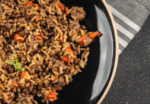 sauteed beef, rice, peppers, and onions are piled on a black plate with grey napkin. Testosterone boosting meals can be really savory like this and not gross and boring.