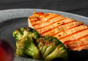 a close up image of a grilled salmon steak and roasted broccoli on a grey plate. testosterone boosting meals like these are favorites for guys who love flavor.