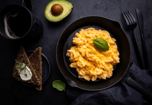 black stoneware serves up multigrain bread, black coffee, a liced avocado and delicious looking scrambled eggs with spinach as part of a testosterone boosting meal protocol.